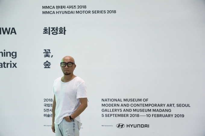 MMCA 현대차시리즈 2018: 최정화–꽃, 숲 展의 최정화 작가가 전시장 앞에서 포즈를 취하고 있는 모습