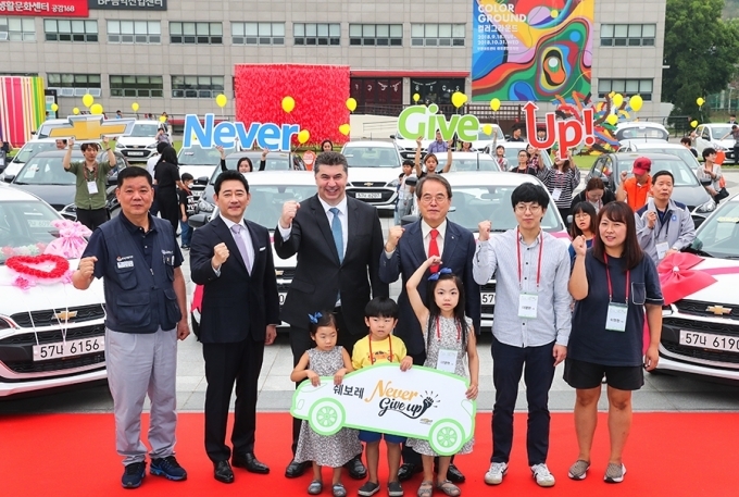 카허카젬 한국지엠 사장(가운데), 전광렬 초록우산 어린이재단 홍보대사(가운데 왼쪽), 임한택 금속노조 한국지엠지부 지부장(맨 왼쪽), 이제훈 초록우산 어린이재단 회장(가운데 오른쪽), 수혜자 가족 이영현씨(37세, 여, 맨 오른쪽) 등 이 날 행사에 참석한 참석자들이 함께 웃고 있는 모습.