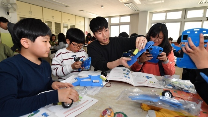 서울 방이초등학교 학생들이 현대모비스가 개최한 주니어공학교실에서 직원 강사의 설명을 들으며직접 만든 스마트카를 작동시켜 보고 있다.