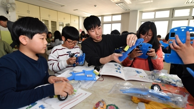 서울 방이초등학교 학생들이 현대모비스가 개최한 주니어공학교실에서 직원 강사의 설명을 들으며 직접 만든 스마트카를 작동시켜 보고 있다.