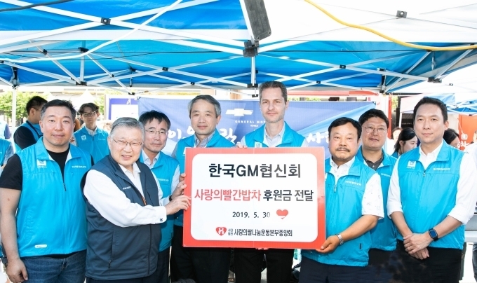 사랑의 빨간밥차 후원금을 전달하고 있는 마르시오 루콘 한국지엠 구매부문 부사장(가운데)과 문승 한국지엠 협신회 회장(가운데 오른쪽)이 기념촬영을 하고 있다.