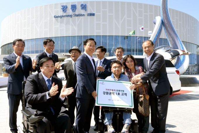 앞줄 좌측부터) 김선규 사단법인 그린라이트 회장, 김대식 기아차 전무, 최문순 강원도지사, (뒷줄 좌측부터) 심영섭 강원도의회 사회문화위원장, 김인호 한국철도공사강원본부장, 원충의 사단법인 강릉시장애인법인단체연합회장, 김한근 강릉시장, 최선근 강릉시의회 의장이 강원권역 초록여행 1호 고객과 함께 기념 촬영을 하고 있는 모습.