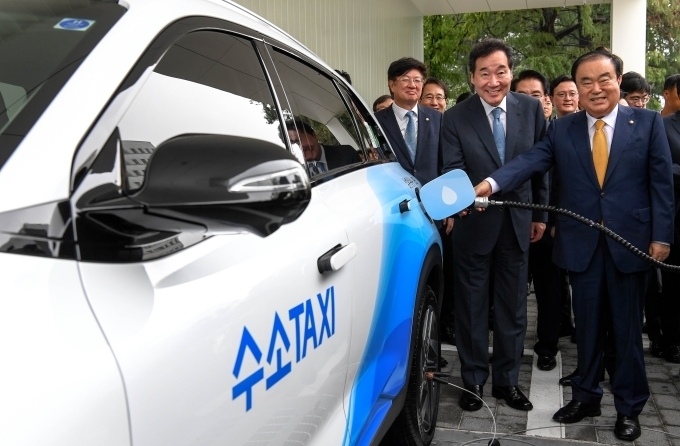 앞줄 오른쪽부터 문희상 국회의장, 이낙연 국무총리가 수소전기택시에 수소를 충전을 하는 모습