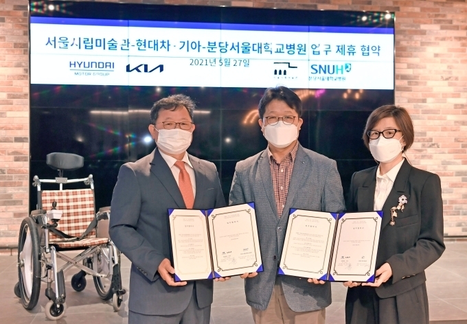 27일 서울 서초구 소재 제로원에서 진행된 업무협약(MOU) 체결식에서 (왼쪽부터) 분당서울대학교병원 김지수 기획조정실장, 기아 신동수 경영전략실장, 서울시립미술관 백지숙 관장이 자율주행 시스템이 탑재될 전동 휠체어 앞에서 기념 사진을 촬영하고 있다.