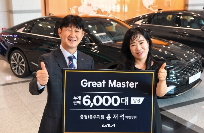 누계 판매 6000대를 돌파한 충주지점 홍재석 영업부장이 아내와 함께 기아 양재사옥에서 기념 촬영을 하고 있는 모습.