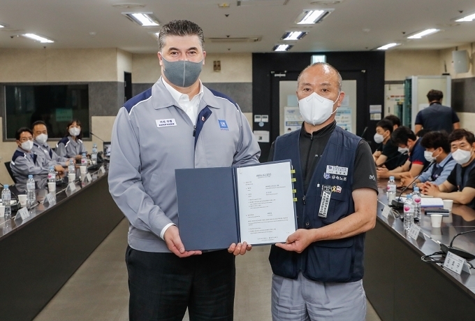 카허 카젬 한국지엠 사장(왼쪽), 금속노조 한국지엠지부 김성갑 지부장(오른쪽)이 2021년 임단협 합의서에 서명 후 합의서를 들고 기념 촬영을 하는 모습.