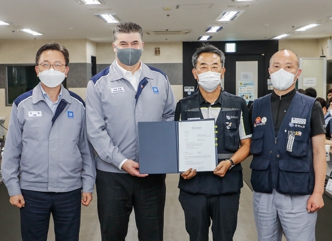 (왼쪽부터) 한국지엠 최종 부사장, 한국지엠 카허 카젬 사장, 금속노조 김호규 위원장, 금속노조 한국지엠지부 김성갑 지부장이 2021년 임단협 합의서에 서명 후 합의서를 들고 기념 촬영을 하는 모습.