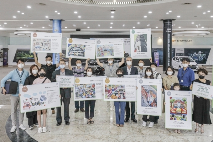 12일 개최된 그림 그리기 대회 시상식에 참여한 GM 한국사업장 리더십 및 직원과 가족들이 그림을 들고 있는 모습.