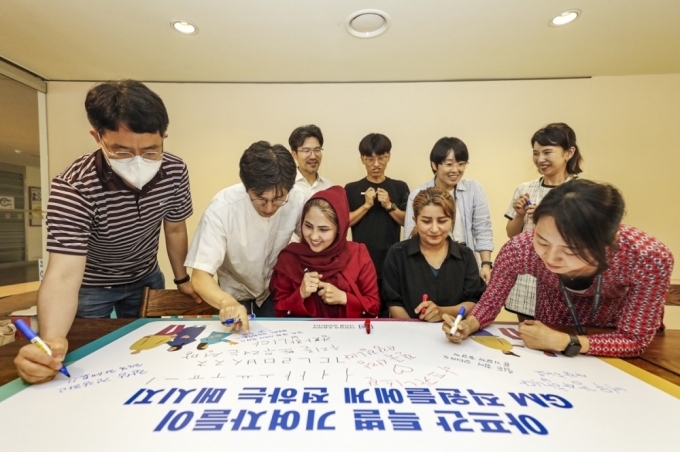 아프간 특별 기여자 사자디 마르지아씨, 호싸니 파티마씨(맨 앞 가운데 왼쪽부터) 및 GM 임직원들이 서로에게 응원의 메시지를 써주고 있는 모습.