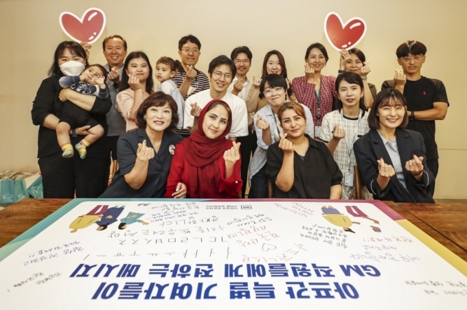주영신 연수구가족센터장(맨 앞 왼쪽), 아프간 특별 기여자 사자디 마르지아씨, 호싸니 파티마씨(맨 앞 가운데 왼쪽부터), 염지연 지엠한마음재단코리아 사무국장(맨 앞 오른쪽) 및 GM 임직원들이 단체사진을 촬영하고 있는 모습.