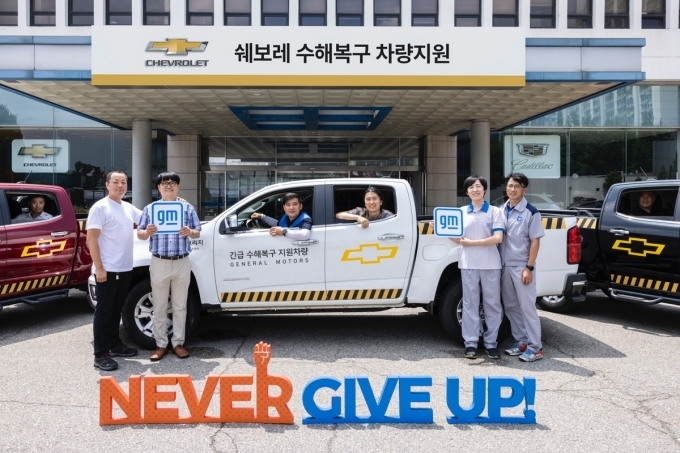 GM 임직원들이 집중호우 피해 복구를 위해 전달되는 구호 차량 앞에서 빠른 일상회복을 기원하고 있는 모습.