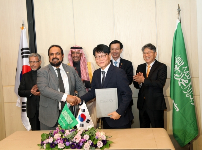 KG 모빌리티 정용원 대표이사(사진 앞줄 오른쪽)와 SNAM사 파하드 알도히시 사장이 MOU를 체결하고 악수를 하고 있으며, KG 모빌리티 곽재선 회장, 산업통상자원부 방문규 장관, 사우디 산업광물자원부 반다르 이브라임 알코라이예프 장관, SNAM사 무함마드 알 트와이즈리 회장이 축하해 주고 있다.(사진 뒷줄 오른쪽부터)