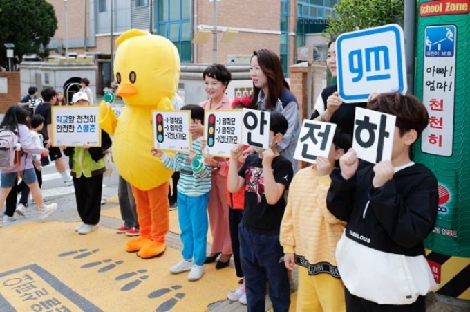 29일 인천 동수 초등학교에서 진행된 ‘안전하게 건너요’ 캠페인에서 GM 커뮤니케이션 총괄 및 CMO 윤명옥 전무(왼편)를 비롯해 GM 임직원 및 동수 초등학교 학생들이 등교하는 학생들을 대상으로 안전 구호를 외치고 있는 모습.