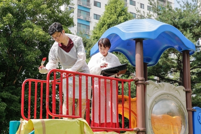 한마음재단 윤명옥 사무총장(오른쪽)을 비롯해 GM 임직원 자원봉사자들이 놀이터 주변 시설을 정비하고 있다.