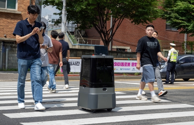 현대차∙기아 로보틱스랩 자율주행 배송로봇이 시민과 함께 횡단보도를 횡단하고 있다.