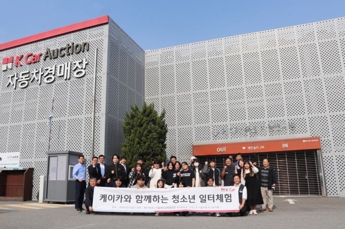 케이카 오산경매장에서 케이카 임직원과 대안학교 재학생, 선생님이 모여 기념 촬영을 하고 있다.