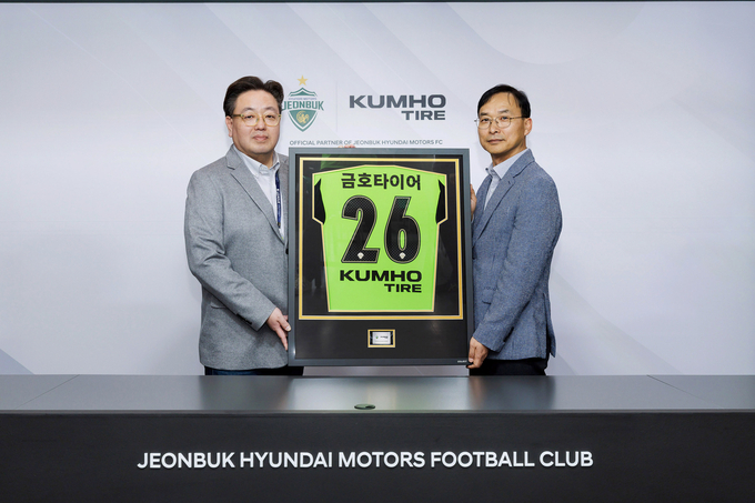 (오른쪽부터) 금호타이어 G.마케팅담당 윤민석 상무와 전북현대모터스 이도현 단장이 공식 파트너십 연장 조인식을 체결하며 금호타이어 로고가 적용된 유니폼 액자를 들고 기념사진을 찍고 있다.